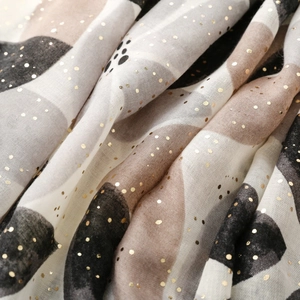 Detailaufnahme eines weichen Leinenschals mit eleganten Goldfolien-Punkten und Farbblöcken