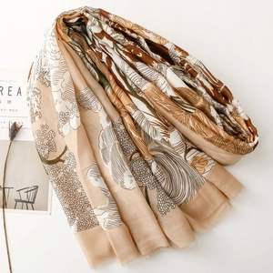 Détail d'une écharpe en coton et lin avec motifs de forêt dorée et franges fines