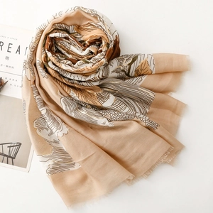 Détail d'une écharpe en coton lin avec imprimé jungle doré et bords à franges sur magazine