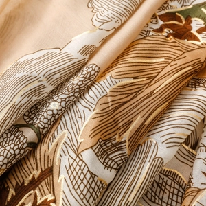 Détail macro d'une écharpe en coton et lin beige avec imprimé feuille doré