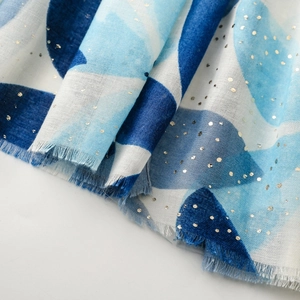 Nahaufnahme von blauem Leinenschal mit Goldfolienpunkten und Fransenkante
