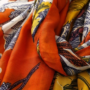 Détail macro de l'écharpe avec motif de forêt tropicale dorée sur tissu orangé