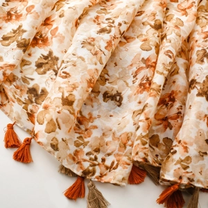 Detail view of floral print scarf fabric with bohemian orange tassels and soft texture