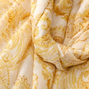 Macro shot of yellow paisley cotton linen scarf fabric showing soft drape and texture