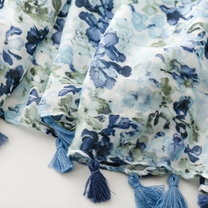 Detail of floral linen scarf showing blue flower prints and long tassel trim edges