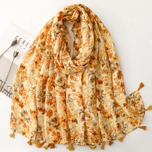 Detail of floral linen shawl featuring long tassels and vibrant orange summer pattern
