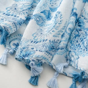 Detail of paisley print linen scarf with blue tassels and soft woven fabric texture