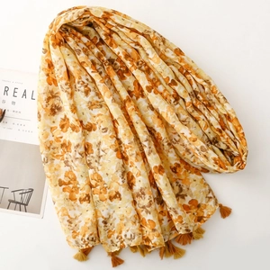 Detailed view of yellow floral cotton linen scarf with elegant fringe and magazine prop