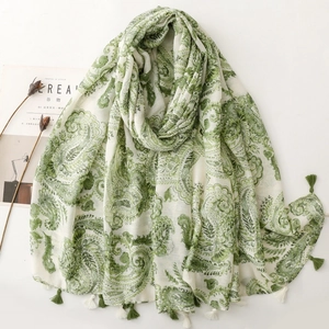 Detail of white cotton scarf with green paisley patterns and fringed tassels on edges