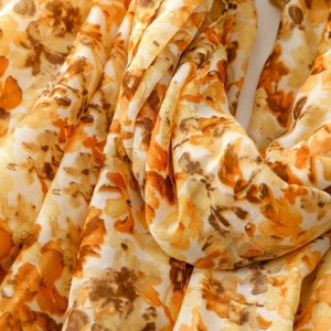Detail of floral cotton linen scarf featuring warm orange and yellow botanical patterns