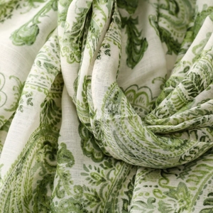 Close-up of linen-feel fabric showing detailed green paisley patterns and woven texture