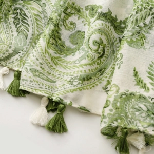 Detail of green paisley print cotton scarf featuring decorative two-tone fringe tassels