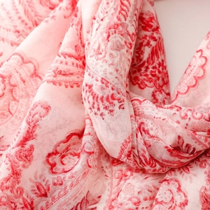 Detail shot of lightweight pink linen scarf with red paisley patterns and soft texture