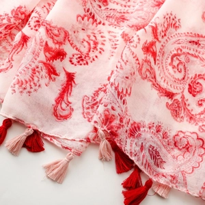 Macro shot of breathable fabric with red paisley pattern and fringe trim details