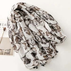 Detail of floral ginkgo print on beige linen scarf with decorative fringe tassels