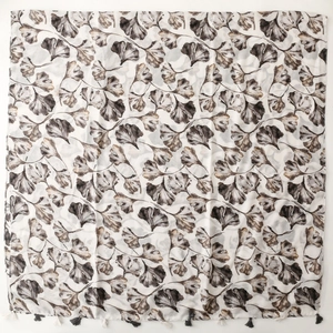 Detailed view of white scarf with gray ginkgo leaf print and tassel trim edges