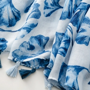 Detail of blue ginkgo leaf print on lightweight white scarf with delicate tassels