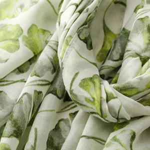 Macro detail of breathable white scarf fabric featuring green ginkgo leaf print patterns