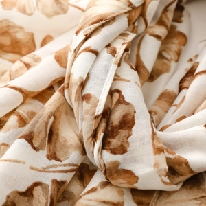 Detailed view of white cotton-linen scarf with brown leaf pattern and fine hem stitch