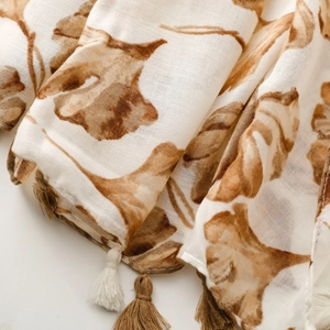 Detailed close-up of a floral print scarf featuring ginkgo leaves and soft fringe tassels