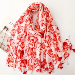 Red and white scarf with ginkgo leaf print and tassel trim on a white background