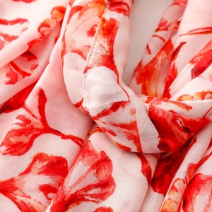 Macro detail of red floral print on lightweight pink scarf fabric with fine stitching