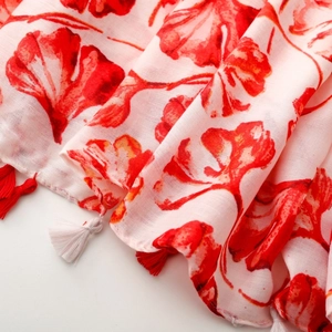 Detail of botanical ginkgo leaf print on light linen-feel scarf with red fringe tassels