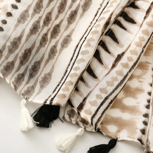 Detailed macro view of ethnic geometric patterns and tassel fringe on linen-feel scarf
