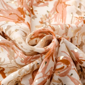 Détail d'une écharpe en coton et lin avec des points dorés et un motif floral