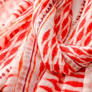 Detailed close-up of soft red and cream scarf fabric with tribal geometric patterns