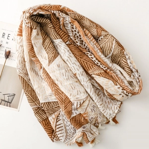 Detail of earthy tones scarf with palm leaf prints and bicolour tassel pendants decor