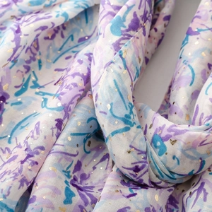 Détail d'une écharpe en lin aux motifs floraux violets et points dorés brillants