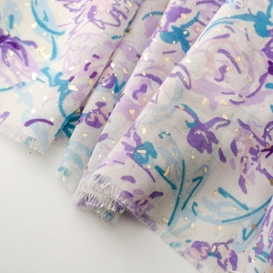 Détail d'une écharpe fleurie avec accents dorés et bords effilochés naturels