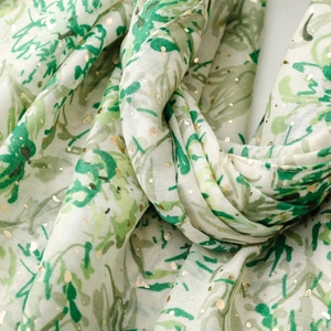 Gros plan sur l'écharpe en coton et lin avec détails dorés et imprimés de feuilles vertes