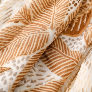 Macro detail of breathable palm leaf print scarf with soft earth tones and linen texture