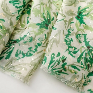 Détail d'une écharpe femme à motif feuilles vertes avec dorures et bords frangés