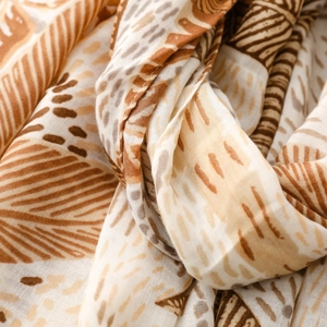 Detail of bohemian scarf fabric with coconut tree prints and soft earth tones texture