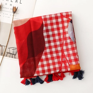Detail of red and white checkered scarf with geometric patterns and red fringe tassels