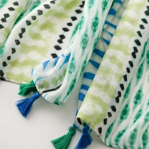 Detail of soft linen-touch scarf with geometric print and vibrant silk fringe tassels