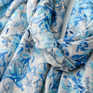 Détail de l'écharpe en coton et lin avec imprimés floraux bleus et pois dorés brillants