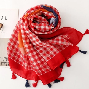 Macro detail of red and white checkered scarf with colorful tassel fringe accents