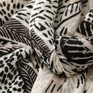 Close-up of bohemian scarf showing soft draped fabric with palm leaf and dot patterns