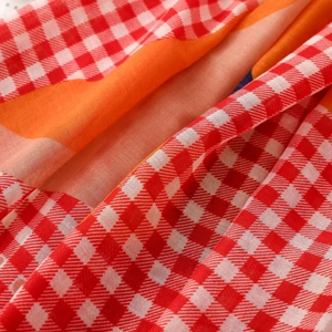 Close-up of lightweight Bali yarn scarf showing red gingham and vibrant floral print