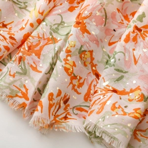 Détail d'une écharpe florale toucher lin avec accents dorés et bords effilochés