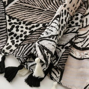 Detailed view of bohemian leaf print scarf featuring monochrome patterns and fringe edges