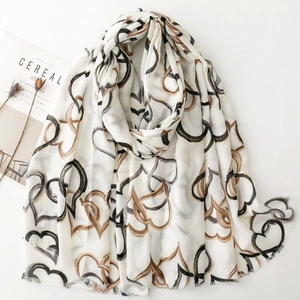 White linen-feel scarf with large gold and black heart prints and fringed edges