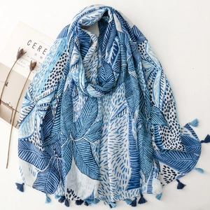 Blue palm leaf printed scarf with tassels and breathable fabric laid flat on a white surface