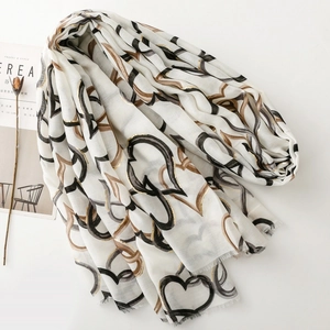 Detail of white cotton scarf featuring gold foil heart patterns and soft fringe edges