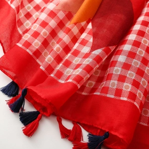 Detail of red and white checkered scarf featuring vibrant color blocks and handmade tassels