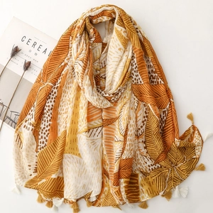 Detail of yellow and orange scarf featuring fringe tassels and abstract leaf patterns